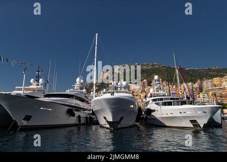 Molti yacht enormi sono nel porto di Monaco nelle giornate di sole, Monte Carlo, la montagna è sullo sfondo, bordo lucido del motoscafo, Foto Stock