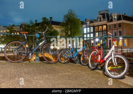 Ciclismo Famiglia :) sul canale Embankment di Amsterdam di notte Foto Stock