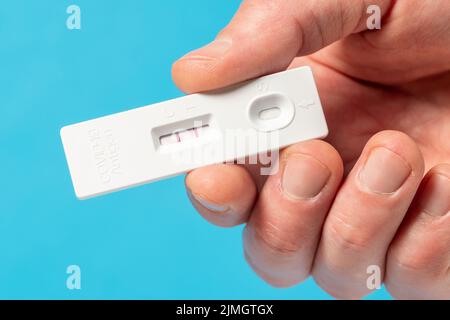 Mano che mostra il risultato positivo del test Covid-19 con il kit per test SARS COV-2 Rapid Antigen Foto Stock
