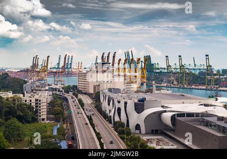 L'enorme porto logistico più trafficato di Singapore, molte gru per spostare container, enormi navi da carico sullo sfondo, negozi m Foto Stock