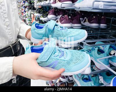 Mosca, Russia, marzo 2022: Qualcuno sceglie sneakers blu per bambini o donne nel negozio di articoli sportivi Decathlon. Foto Stock