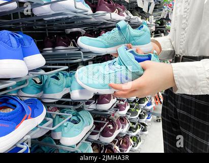 Mosca, Russia, marzo 2022: Qualcuno sceglie sneakers blu per bambini o donne nel negozio di articoli sportivi Decathlon. Foto Stock