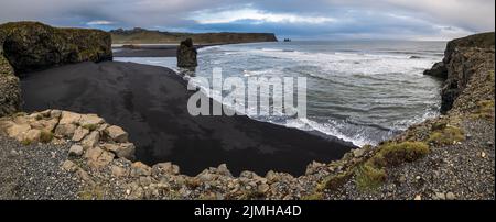 Pittoresca vista autunnale serale della spiaggia di sabbia vulcanica nera dell'oceano di Reynisfjara e delle formazioni rocciose da Capo di Dyrholaey, Vik, SO Foto Stock