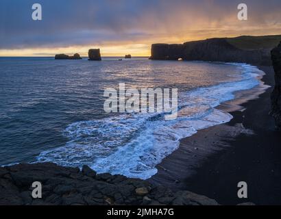 Pittoresca autunno sera vista del Capo Dyrholaey, spiaggia e formazioni rocciose. Vik, Islanda del Sud. Foto Stock
