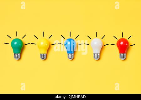 Layout creativo con lampadine multicolore su sfondo giallo. Foto Stock