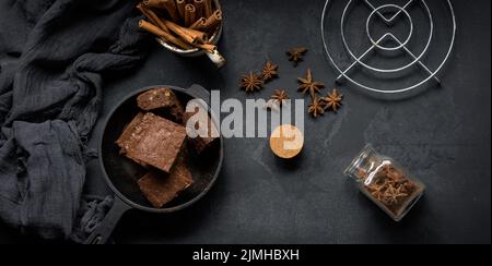 Pezzi di brownie al forno in una padella nera in metallo sul tavolo, vista dall'alto Foto Stock