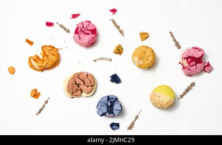 Macaron rotondi spezzati con briciole su sfondo bianco, dessert delizioso, vista dall'alto Foto Stock