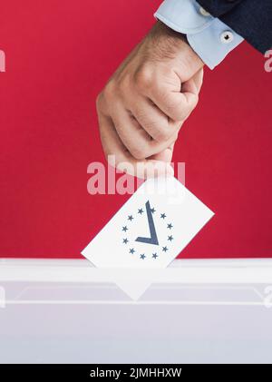 Uomo che mette il ballottaggio casella con sfondo rosso Foto Stock