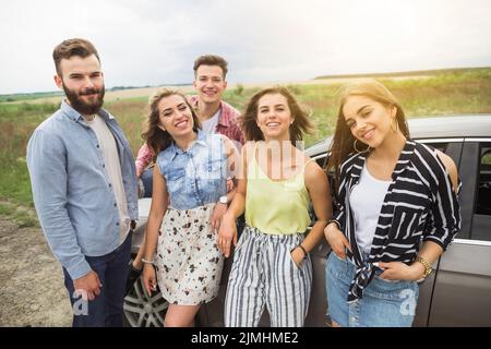 Ritratto amici felici in piedi campo vicino auto Foto Stock