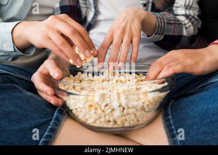 Ciotola con popcorn mani ragazza seduta a croce gambe divano Foto Stock