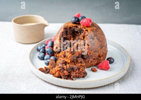 Tradizionale budino di prugna australiano come primo piano con frutta e salsa di rum alla vaniglia su un piatto da dessert dal design moderno con spac copia Foto Stock