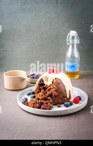 Budino di prugne australiano tradizionale come primo piano con frutta e salsa di rum alla vaniglia su un piatto da dessert con spazio copia Foto Stock