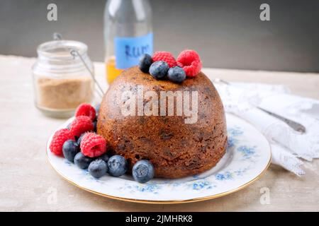 Budino di prugne australiano tradizionale come primo piano con frutta su un piatto da dessert con spazio copia Foto Stock