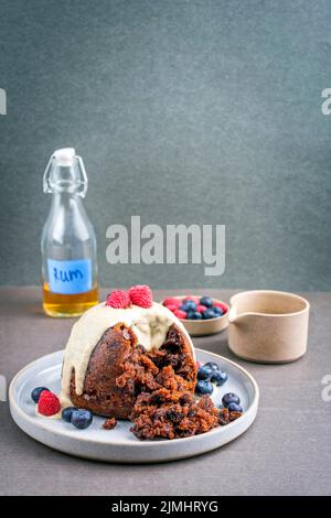 Budino di prugne australiano tradizionale come primo piano con frutta e salsa di rum alla vaniglia su un piatto da dessert con spazio copia Foto Stock