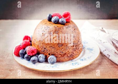 Budino di prugne australiano tradizionale come primo piano con frutta su un piatto da dessert con spazio copia Foto Stock