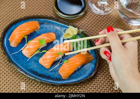 Delizioso nigirizushi di salmone di prima qualità su piatto blu Foto Stock