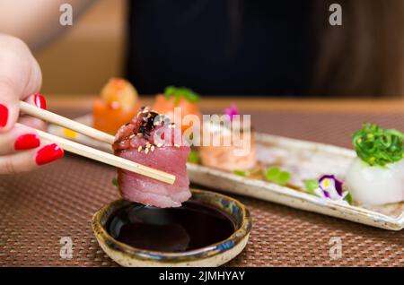 Donna che mangia delizioso sushi, primo piano su bacchette. Foto Stock