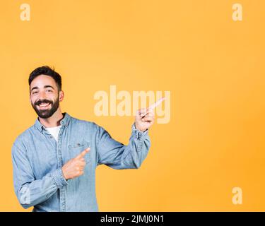 Un ragazzo sorridente a scatto medio che indica Foto Stock