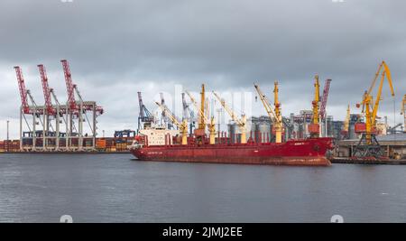 Nave mercantile commerciale durante le operazioni di carico al porto di Odessa sullo sfondo delle gru di carico durante il tramonto. Per la prima volta dall'inizio della guerra russa di aggressione contro l'Ucraina, una nave che trasporta grano ha lasciato il porto di Odessa. Questo dovrebbe rendere milioni di tonnellate di grano disponibile di nuovo per il mercato mondiale. Prima della guerra di aggressione russa, l'Ucraina era uno dei più importanti esportatori di grano al mondo. Per loro, sono in gioco miliardi di entrate derivanti dalla vendita di grano e mais, tra le altre materie prime. Foto Stock