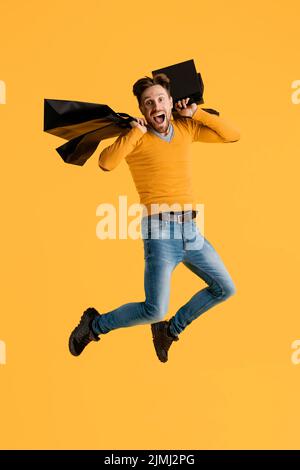 Giovane uomo con i sacchetti di shopping che saltano Foto Stock