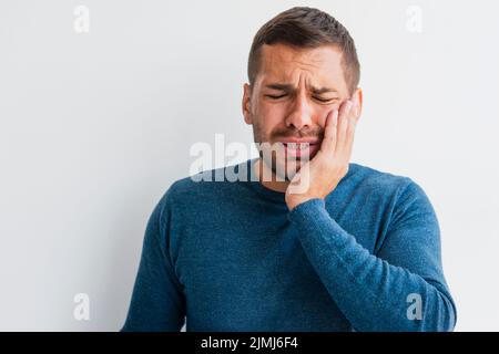 Uomo con dolore che tiene una mano faccia Foto Stock