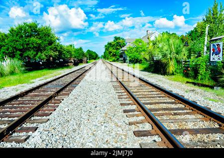 I binari ferroviari passano davanti all'Ocean Springs L&N Depot, ora sede della Camera di Commercio e dell'Ufficio del turismo di Ocean Springs, in Ocean Springs, Mississippi. Foto Stock