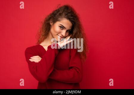 Giovane bella gentile cute curly brunette donna con emozioni sincere poising isolato su sfondo parete con copia spazio indossare Foto Stock