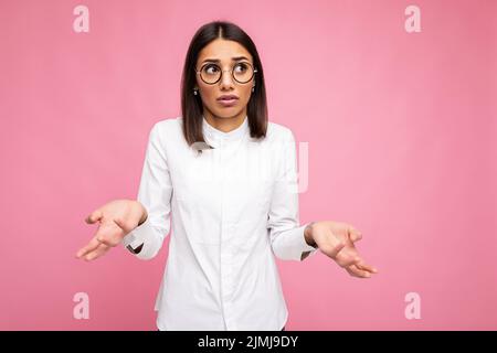 Foto di bella donna che chiede triste giovane brunetta indossando abiti casual e occhiali ottici alla moda isolato su colorfu Foto Stock