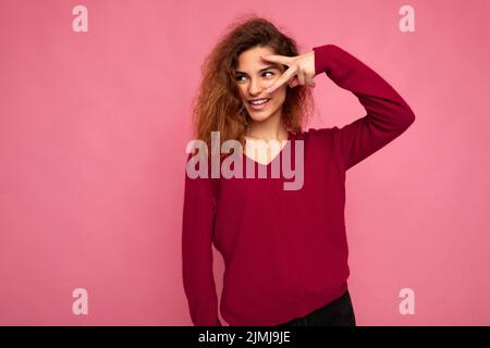 Ritratto di giovane emotivo positivo felice sorridente bella brunetta curly donna con emozioni sincere indossando alla moda rosa swea Foto Stock