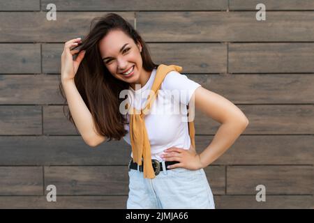 Foto di bella bella bella sorridente felice positivo affascinante giovane bruna giovane donna che indossa abiti alla moda: Bianco t Foto Stock