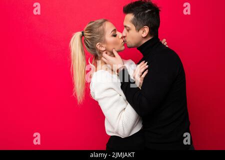Foto di una bella giovane bionda donna bianco maglia maglione e un adulto brunetto con stoppia in un maglione nero che sono ki Foto Stock