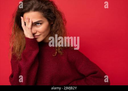 Giovane attraente curly brunette donna con emozioni sincere poising isolato sulla parete di sfondo con copia spazio indossando Foto Stock