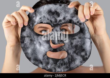 Donna con maschera bolla foglio sul suo viso Foto Stock