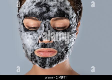 Donna con maschera bolla foglio sul suo viso Foto Stock