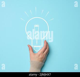 La mano della donna e una lampada elettrica disegnata su uno sfondo blu. Il concetto di ricerca di idee e soluzioni, brainstorming. Int Foto Stock