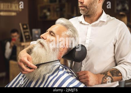 Bell'uomo anziano che ottiene styling e rifilatura della sua barba Foto Stock