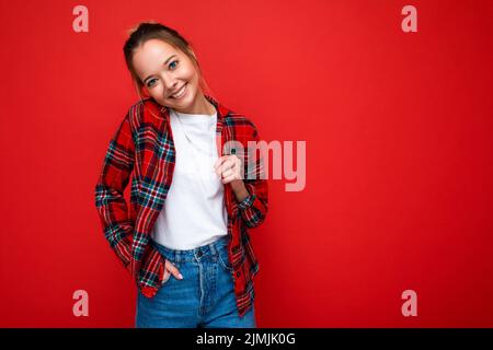 Giovane bella donna in elegante camicia rossa hipster e casual t-shirt bianca per mockup. La femmina positiva mostra emozioni facciali. F Foto Stock