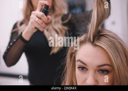 Crop parrucchiere applicando capelli spray Foto Stock