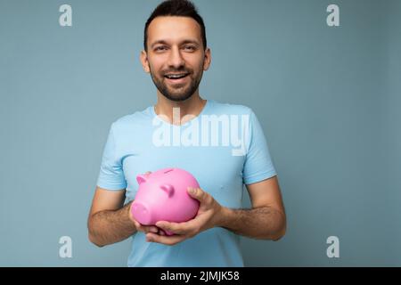 Foto di felice carino sorridente giovane bello brunetto unshaven uomo con barba con emozioni sincere indossando casual t-shirt blu isol Foto Stock