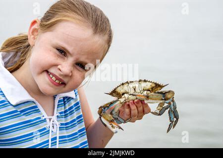 Virginia Newport News vicino a James River Bridge, attività ricreative granchio acqua ragazza femmina colto granchio, tiene bambini in attesa, turisti vacanza Foto Stock