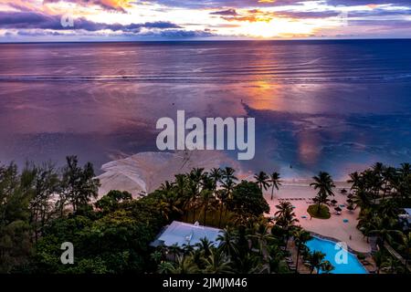 Vista aerea: Africa, Mauritius, tramonto sulla costa di Flic en Flac, un fiume lava acqua fangosa nel mare dopo una doccia con la pioggia Foto Stock