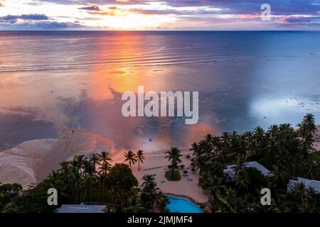 Vista aerea: Africa, Mauritius, tramonto sulla costa di Flic en Flac, un fiume lava acqua fangosa nel mare dopo una doccia con la pioggia Foto Stock