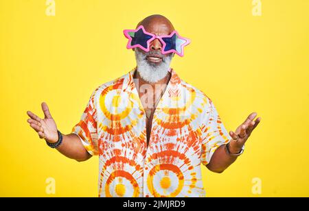 Incolparlo sull'uomo di swag. Ritratto di un uomo anziano funky ed elegante che indossa occhiali da sole in posa in studio su uno sfondo giallo. Foto Stock