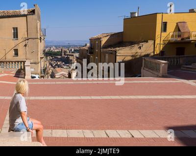 Una donna guarda le scale di Santa Maria del Monte e dietro la chiesa di Ciesa San Francesco d'Assisi. Foto Stock