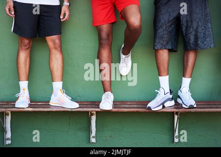 Sei pronto a potenziare il tuo gioco. Primo piano di un gruppo di uomini sportivi in piedi su una panca contro un muro. Foto Stock