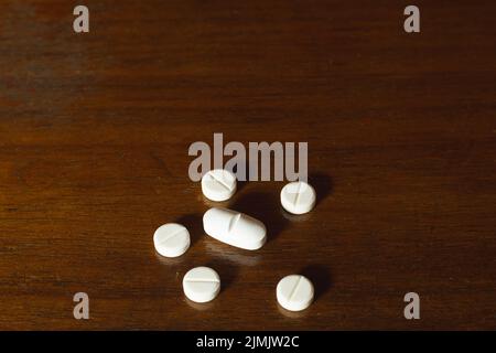 Semplice pila di pillole bianche, medicine, pillole impilate su sfondo marrone. Forniture mediche. Foto Stock