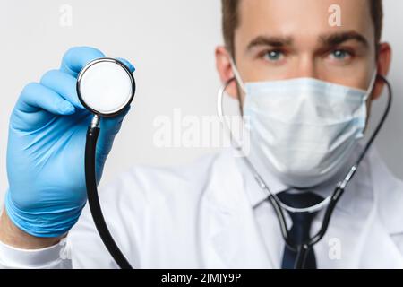 Medico con lo stetoscopio indossare maschera di prevenzione e guanti in lattice Foto Stock