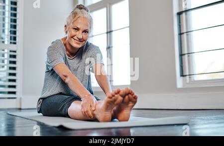 Remamber per riposare in mezzo. Ritratto di una donna matura allegra che pratica yoga all'interno di uno studio durante il giorno. Foto Stock