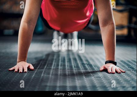 Forte è la sua impostazione di default. Una giovane atleta irriconoscibile che si sta allenando in palestra. Foto Stock