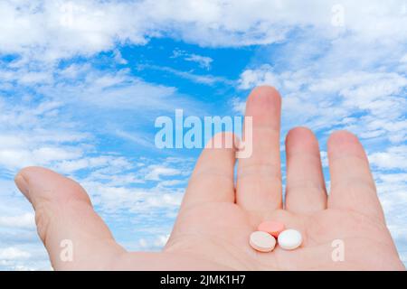 Pillole bianche e rosa nel palmo della mano. Trattamento con pillole. Foto Stock